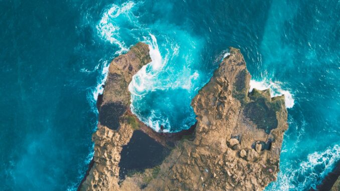 photo of brown rocks between blue body of water by deb1909 (Unsplash.com)